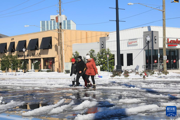   1月22日，在美国路易斯安那州新奥尔良，人们从暴风雪后的街头走过。新华社发（魏兰摄）