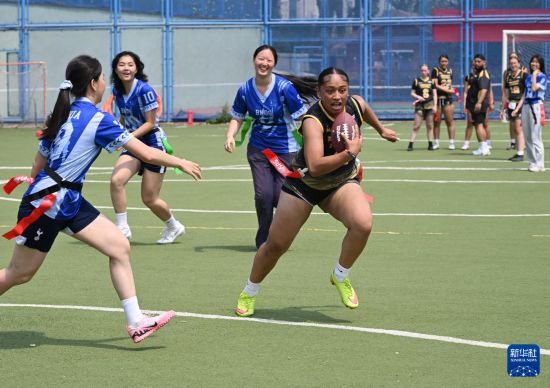 5月26日，美国华盛顿州林肯高中女子腰旗橄榄球队队员同北京市十一学校学生在球场上进行友谊赛。新华社记者 李贺 摄