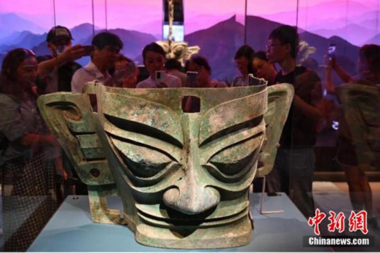 2024年6月27日，“探秘古蜀文明——三星堆与金沙”展览在北京大运河博物馆(首都博物馆东馆)开幕，265件(套)文物与观众见面。图为观众在参观、拍摄青铜大面具(商)。中新社记者 田雨昊 摄
