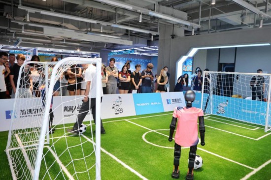 8月7日，外国青年在北京亦庄“机器人大世界”观看机器人足球赛。（林丽园 摄）