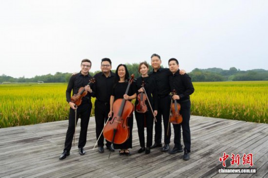 10月14日,费城交响乐团的成员在杭州良渚古城遗址公园合影。中新社记者 吴君毅 摄