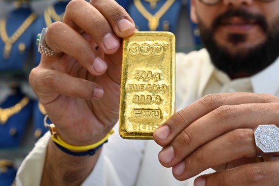 10月23日，在科威特首都科威特城，一名男子在金店内展示500克的金条。新华社发（阿萨德摄）